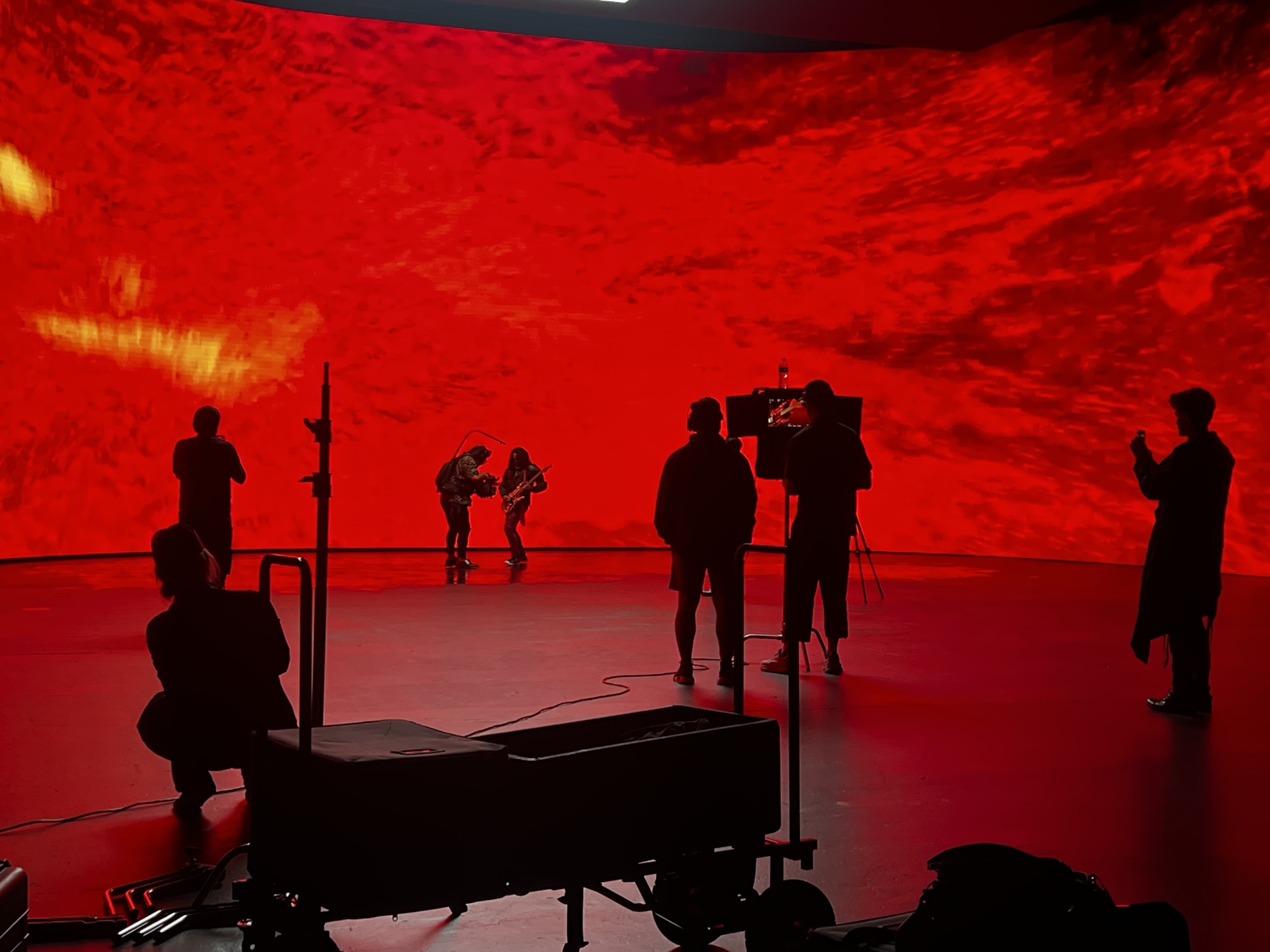 Production crew silhouetted against a large-scale curved LED wall during a shoot